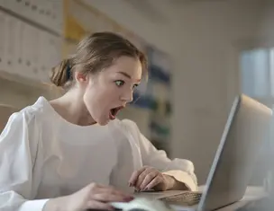 surprised worker behind laptop