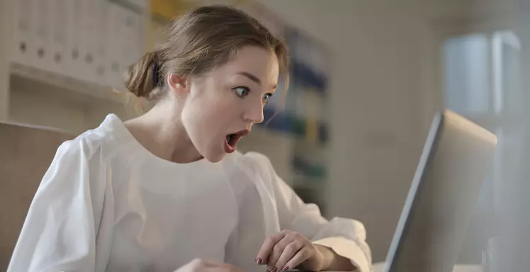 surprised worker behind laptop